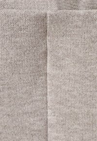 Lichtgrijze gebreide stof met een zachte textuur, met een gestikte naad die verticaal in het midden loopt. Materiaal lijkt warm en casual.