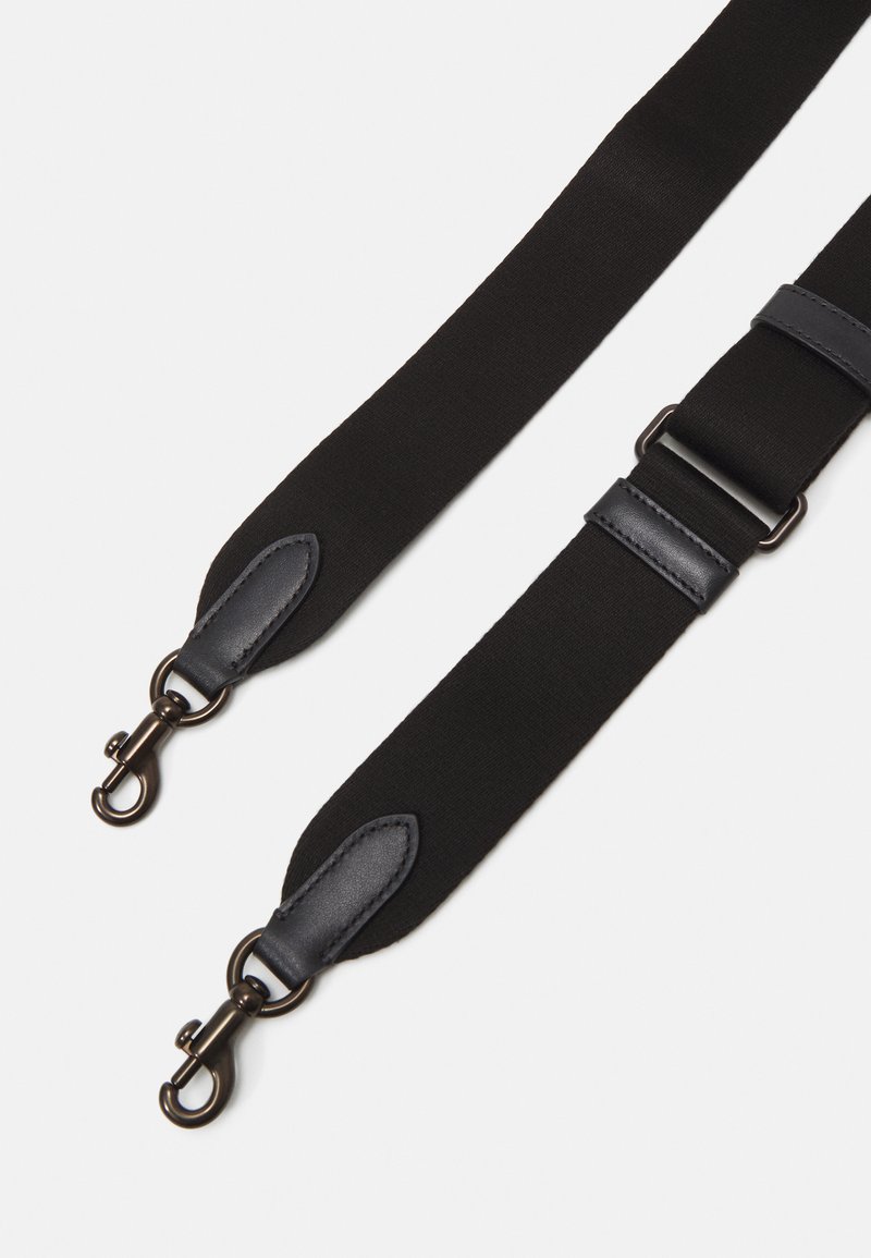 Correa ajustable negra hecha de nailon con acentos de cuero. Presenta clips de metal y una textura suave. Dos puntos de sujeción para versatilidad.