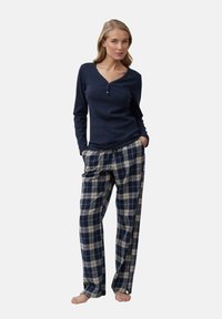 Top de manga larga azul marino con escote en V y botones, combinado con pantalones de pijama de cuadros en azul marino, crema y Beige, con un corte relajado.