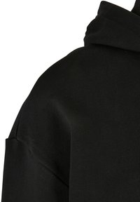 Czarna bluza z kapturem o prążkowanej fakturze, z kieszenią kangurką i grubym sznurkiem do ściągania. Tkanina wydaje się miękka i wytrzymała.