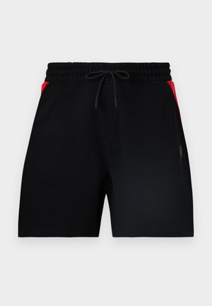 Shorts de sport noirs avec une ceinture élastique, un cordon de serrage et des accents rouges sur les parties supérieures latérales.