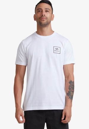 T-shirt blanc à manches courtes avec une poche sur le devant, ornée d'un logo en contour carré noir. Tissu en coton lisse ; coupe décontractée.