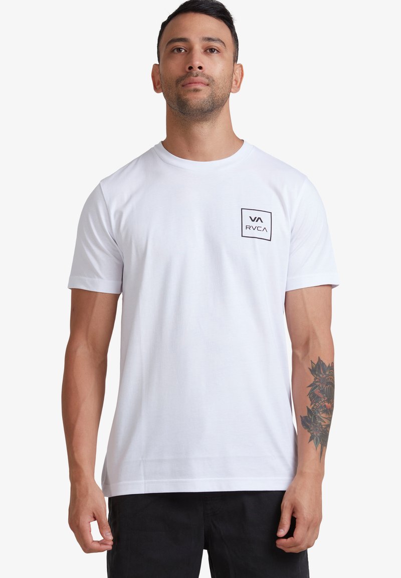 T-shirt blanc à manches courtes avec une poche sur le devant, ornée d'un logo en contour carré noir. Tissu en coton lisse ; coupe décontractée.