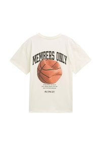 Krēmkrāsas kokvilnas T-krekls ar basketbola grafiku un tekstu "TIKAI LOCEKĻI" uz muguras. Tam ir brīvs piegriezums un īsas piedurknes.
