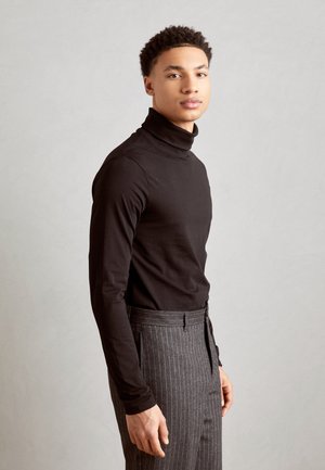 Sort rullekrave trøje parret med grå nålestribede bukser. Stoffet ser glat ud, med et tætsiddende design og medium tykkelse.
