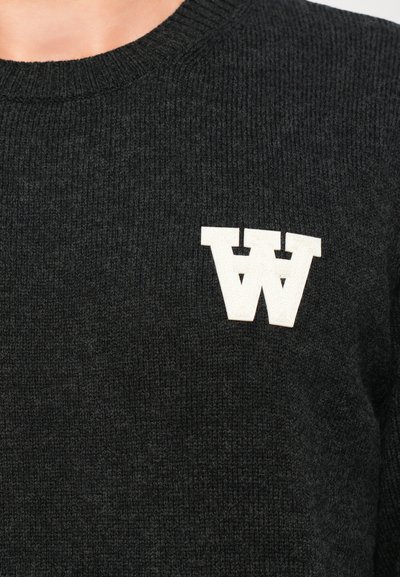 Schwarzer gestrickter Pullover mit geripptem Muster und einem auffälligen weißen "W"-Logo auf der Brust. Runde Ausschnittlinie und taillierte Form.