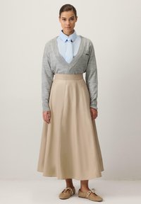 Hall hallatud kampsun hele sinise särgi ja lipsuga, mida täiendab beež põlvpikkune lehvikseelik ning heledad jalanõud.