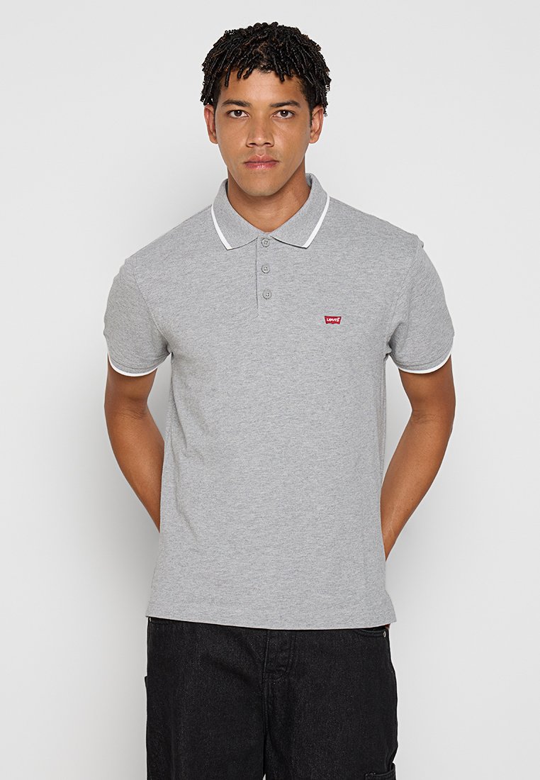 Polo gris avec col et poignets blancs, arborant un petit logo rouge sur la poitrine gauche ; manches courtes et coupe classique.