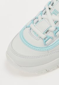 Sneaker bianco con accenti e cuciture azzurri. Presenta una suola in gomma testurizzata, design con lacci e dettaglio del logo di lato.