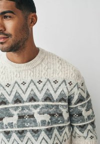 Pullover mit einer cremig weißen Basis, der ein geometrisches Muster in Grau und Braun zeigt, mit Rentiermotiven und strukturiertem Strick.