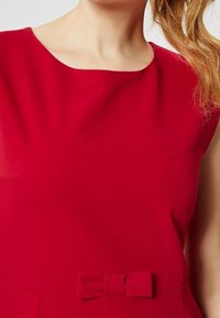 Rotes ärmelloses Kleid mit rundem Ausschnitt, aus glattem Stoff gefertigt, mit einer Schleifenakzentuierung in der Taille und einer figurschmeichelnden Silhouette.