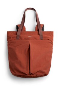 Sac cabas Bellroy couleur rouille avec deux poignées et poches avant plissées, fabriqué en tissu texturé, présenté sur un fond blanc.