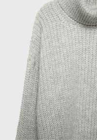 Pull doux gris clair en maille épaisse avec un col roulé haut et des manches longues, présentant un motif côtelé texturé.