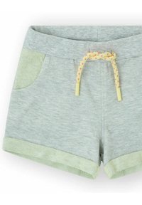 Pantalones cortos grises de tela suave, con detalles verdes en los bolsillos y los dobladillos. Incluye un cordón trenzado amarillo y rosa.