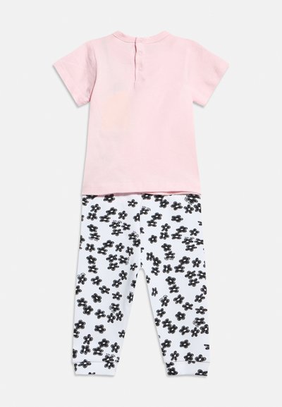 Ροζ ανοιχτόχρωμη μπλούζα για νήπια με κοντά μανίκια και κουμπιά στο πίσω μέρος, συνδυασμένη με λευκό παντελόνι με μαύρο ανθισμένο μοτίβο διασκορπισμένο.
