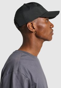 Svart baseballkeps med böjd skärm och justerbart band. Tillverkad av lättviktig tyg, med en subtil lyster och ren design.