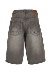 Pleekinud hallid teksapüksid, millel on kaks tagataskut tikitud mustritega ja pruun nahast kaubamärgi märk vöörihmil.