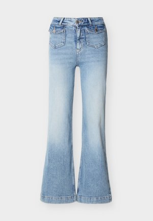 Jean denim bleu clair taille haute avec jambes larges, deux poches à rabat à boutons à l'avant, et une fermeture à bouton et zip.