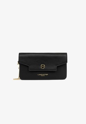 Portefeuille clutch Lancaster Paris en cuir noir avec rabat, bouton pression doré et une courte chaîne en or sur fond blanc.