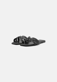 Sandale negre tip slide, cu bretele țesute, talpă plată și o textură fină. Designul este minimalist, fără accente suplimentare.