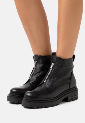 Bottes courtes en cuir noir à finition texturée, équipées de doubles fermetures éclair latérales, semelles en caoutchouc épaisses et un bout arrondi robuste.