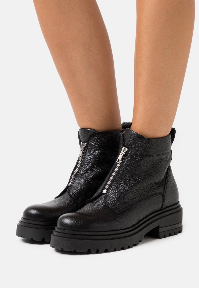 Bottes courtes en cuir noir à finition texturée, équipées de doubles fermetures éclair latérales, semelles en caoutchouc épaisses et un bout arrondi robuste.