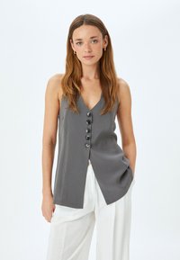 Grijze mouwloze top met een V-hals, voorzien van een knoopsluiting en een rechte snit. Gemaakt van een gladde stof, heeft het een ontspannen pasvorm.