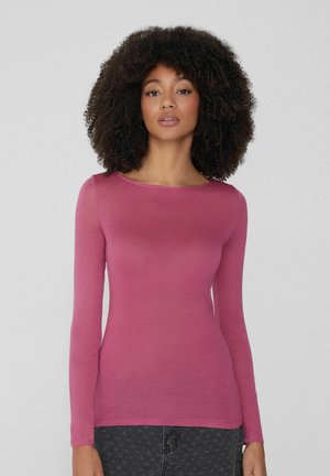 Chemise à manches longues en tissu rose clair et doux avec un col rond et une coupe ajustée. Caractéristiques d'une texture lisse et de détails de couture subtils.