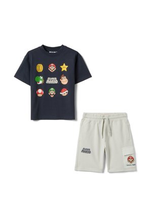 Marineblauw T-shirt met Super Mario-personages en iconen gecombineerd met off-white shorts met Super Mario-logo's en een cargozak.