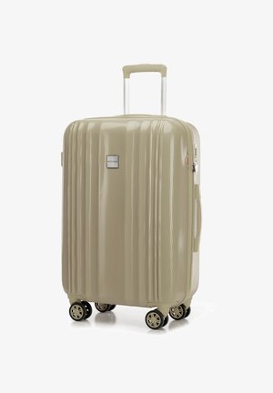 Twarda walizka w beżowym kolorze z teksturowaną powierzchnią, wyposażona w teleskopowy uchwyt i cztery obracające się kółka, co zapewnia łatwość manewrowania.