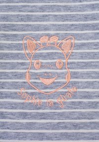 Un tessuto a righe grigio e bianco presenta un volto di giraffa ricamato in rosa chiaro con il testo "Sophie la girafe" sottostante.