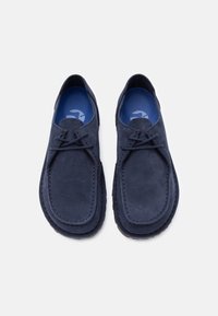 Ζευγάρι σκούρα μπλε μοκασίνια από σουέντ με κορδόνια και μπλε μαλακά πέλματα, σε προβολή από πάνω με λευκό φόντο.