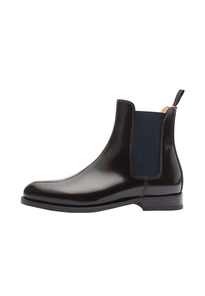 Bota Chelsea negra de cuero con paneles laterales elásticos, punta redondeada y una lengüeta en la parte posterior. Textura suave y suela de goma plana.