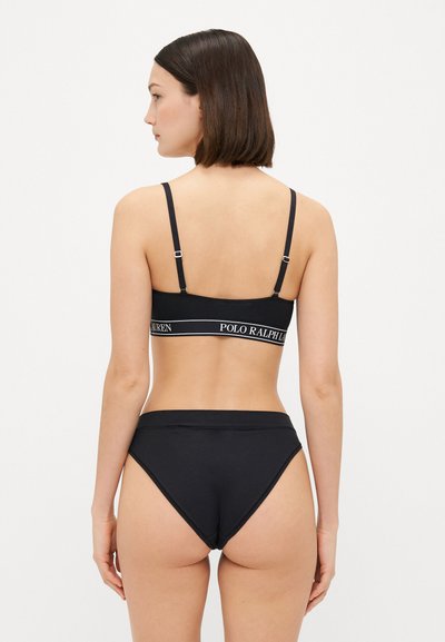 Black lingerie set featuring a bralette with adjustable straps and logo band, paired with high-waisted, seamless bikini bottoms.