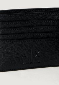 Tarjetero de cuero negro texturizado con múltiples ranuras y el logo en relieve "A|X Armani Exchange".