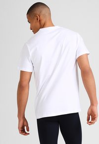 Witte katoenen t-shirt met een ronde halslijn en korte mouwen, met een effen gladde textuur en een reguliere pasvorm. Zichtbare stiksels aan de zoom.