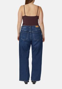 Wijde blauwe spijkerbroeken gemaakt van denim, met een hoge taille, twee achterzakken en een minimalistisch ontwerp. Het model draagt een donker tanktop.