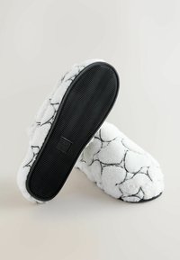 Hvide bløde tøfler med sort geometrisk mønster, tekstureret sål for greb og blødt, blødt overmateriale for komfort.