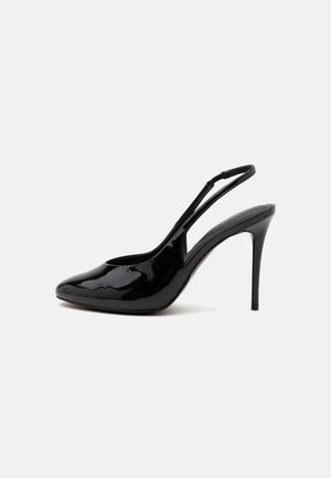 Blank sort højhælet slingback-sko med spids tå og tyndt stilet-hælhæl på en ensfarvet lys baggrund.