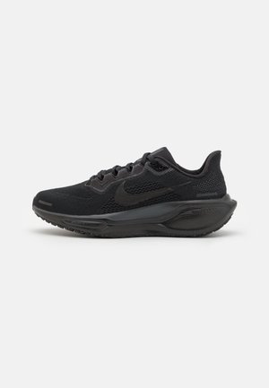 Chaussure de course Nike noire avec tige en mesh, semelle amortie et logo swoosh sur le côté, montrée de profil sur un fond uni.