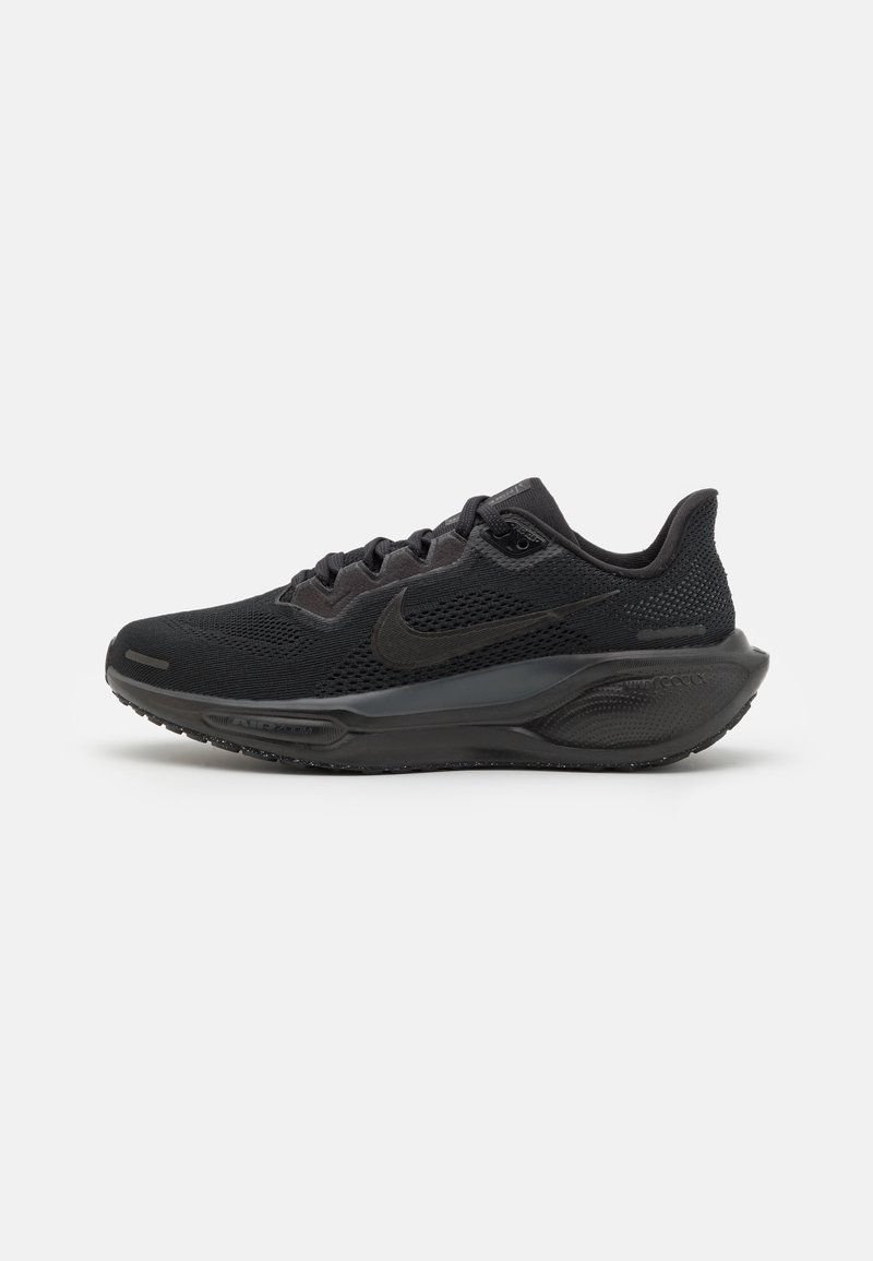 Chaussure de course Nike noire avec tige en mesh, semelle amortie et logo swoosh sur le côté, montrée de profil sur un fond uni.