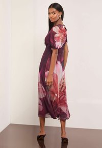 Virágos midi ruha sötét bordó színben, rövid puffujjakkal, nagy rózsaszín és piros virágmintákkal. Áttetsző anyag és lebegő fazon.
