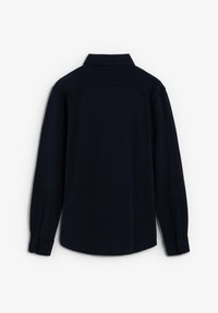 Camisa de manga larga azul marino oscuro con puños abotonados y cuello clásico, mostrada desde la parte trasera sobre un fondo blanco.