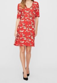 Robe florale rouge avec des manches courtes, détails de boutons sur le devant et un ourlet évasé ; présente des motifs de fleurs crème et vertes.