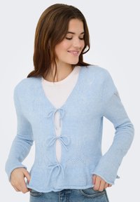Cardigan tricoté bleu clair avec encolure en V, fermeture à cordon et motifs en dentelle décorative. Texture douce avec manches évasées.