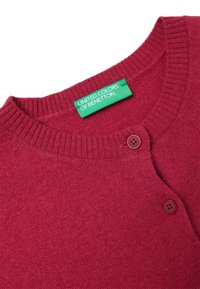 Červený kardigan s kulatým výstřihem, vroubkovanou strukturou, dvěma knoflíky a zelenou etiketou s nápisem "UNITED COLORS OF BENETTON."