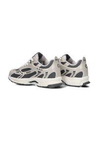 Beige und schwarze Sportschuhe mit Mesh-Einsätzen, strukturiertem Obermaterial, gepolstertem Kragen und charakteristischen Logo-Akzenten an den Seiten und der Ferse.