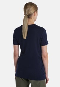 Námořnická modrá krátká rukávová trička s kulatým výstřihem, vyrobená z hladkého materiálu, s rovnými liniemi a bočními akcenty na lemu.
