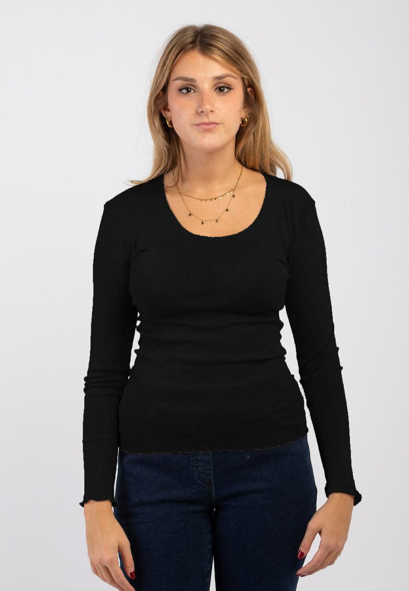 Maglione nero a manica lunga con scollatura a barca, design aderente e polsini sfilacciati. Abbinato a jeans di denim blu.