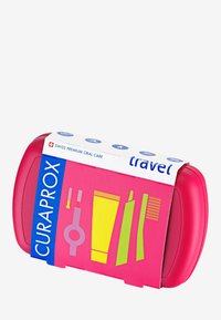 Kit de soins bucco-dentaires de voyage Curaprox en plastique rose vif. Comprend une brosse à dents, du dentifrice et d'autres accessoires illustrés en vert et jaune.